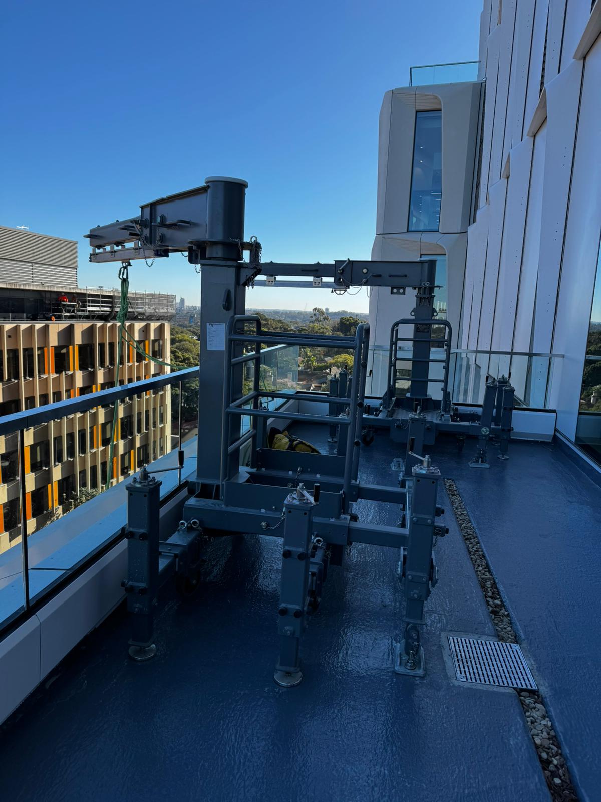 Rope access pony unit mounted on a UNSW rooftop terrace with the campus and treeline behind