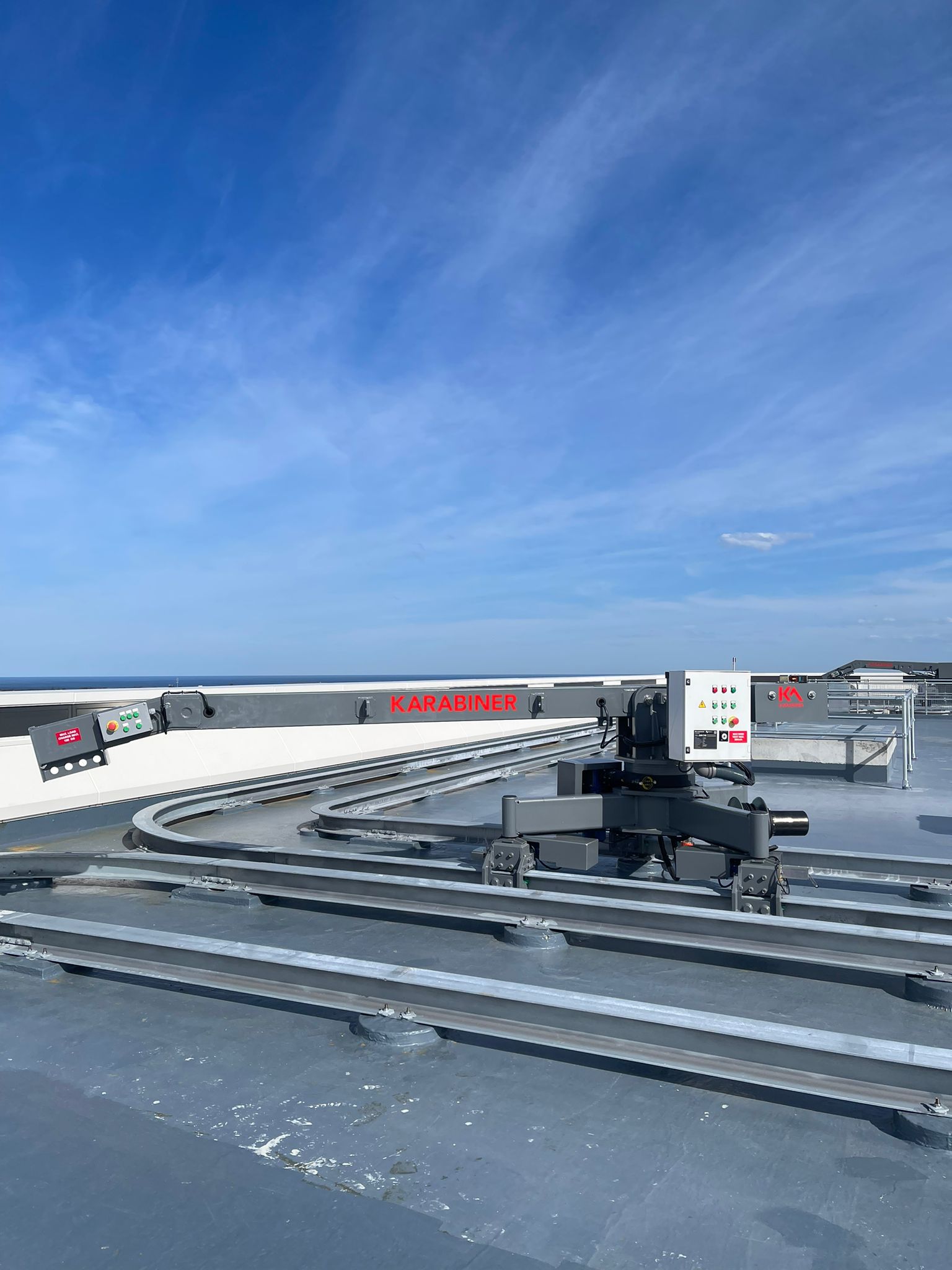 Karabiner branded building maintenance unit on curved roof track at UNSW with clear sky behind