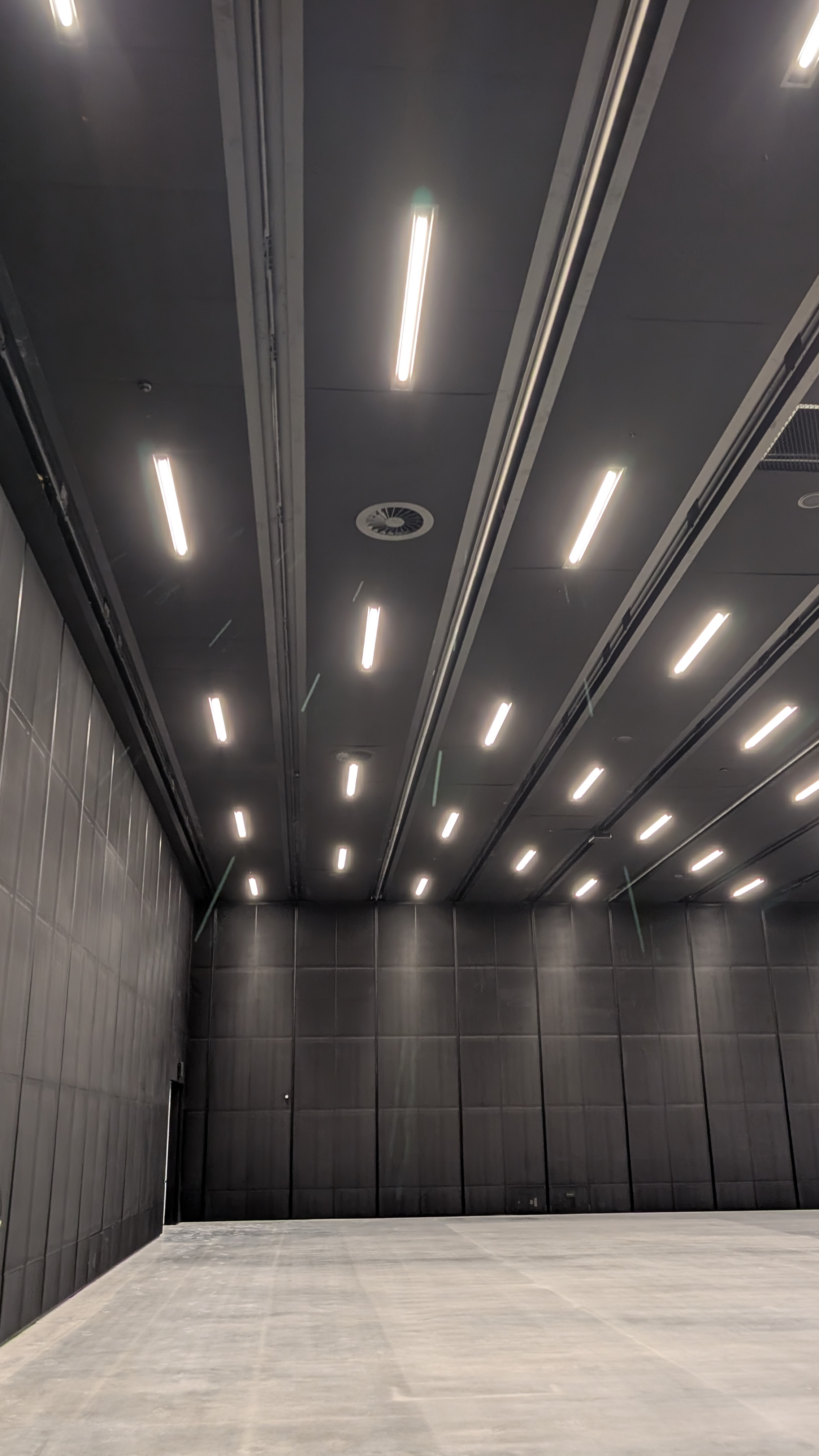 Corner of the dark ceiling and wall in the presentation space, showing the rail line running the length of the soffit